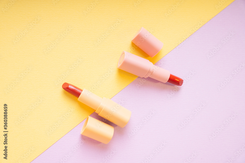 Red lipsticks on yellow and purple background. Top view. Flat lay. Red lipsticks on yellow and purple background. Top view. Flat lay.