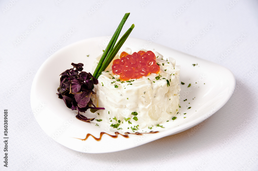 A plate of potato salad with caviar on a white background A plate of potato salad with caviar on a white background