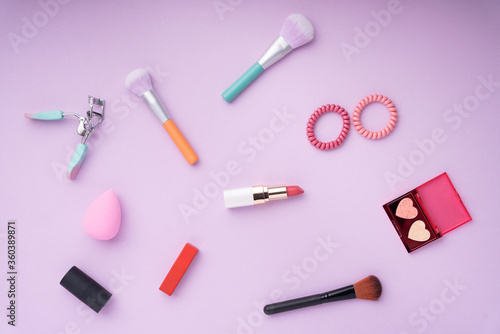 Top view - Colouful cosmetic tools over purple pink background.