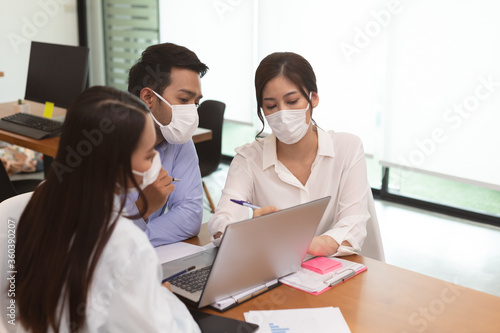 Asian business man and women talk about job and wear masks.New nomal