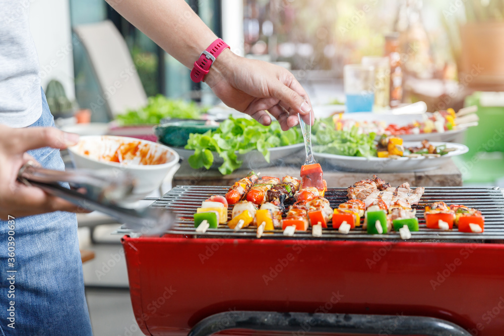 A man grilling pork and barbecue in dinner party. Food, people and family time concept. A man grilling pork and barbecue in dinner party. Food, people and family time concept.