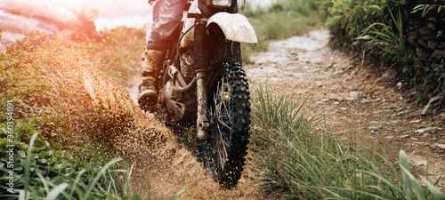 rider on a motorcycle rides a puddle of mud  splashing around photo