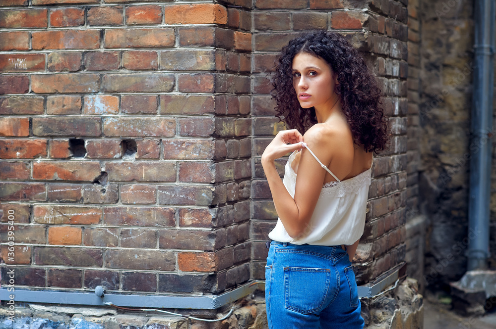 Portrait of a young beautiful woman in the city . A girl in casual clothes poses against an old brick wall Portrait of a young beautiful woman in the city . A girl in casual clothes poses against an old brick wall