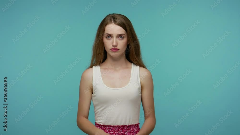 Upset frustrated girl looking down with resentful sad gloomy expression, feeling lonely bored, worrying about troubles, depression negative emotions. indoor studio shot isolated on blue background Upset frustrated girl looking down with resentful sad gloomy expression, feeling lonely bored, worrying about troubles, depression negative emotions. indoor studio shot isolated on blue background