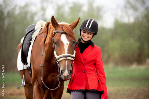 Equestrian sport Woman smile jockey holding horse by bridle outdoors