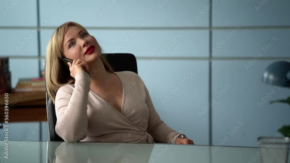 relaxed woman is talking by cell phone in office room at working time relaxed woman is talking by cell phone in office room at working time