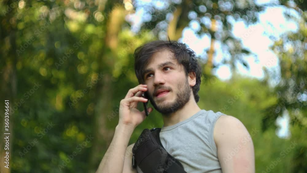 Young man with backpack talking on the phone in the forest.Technology concept Young man with backpack talking on the phone in the forest.Technology concept