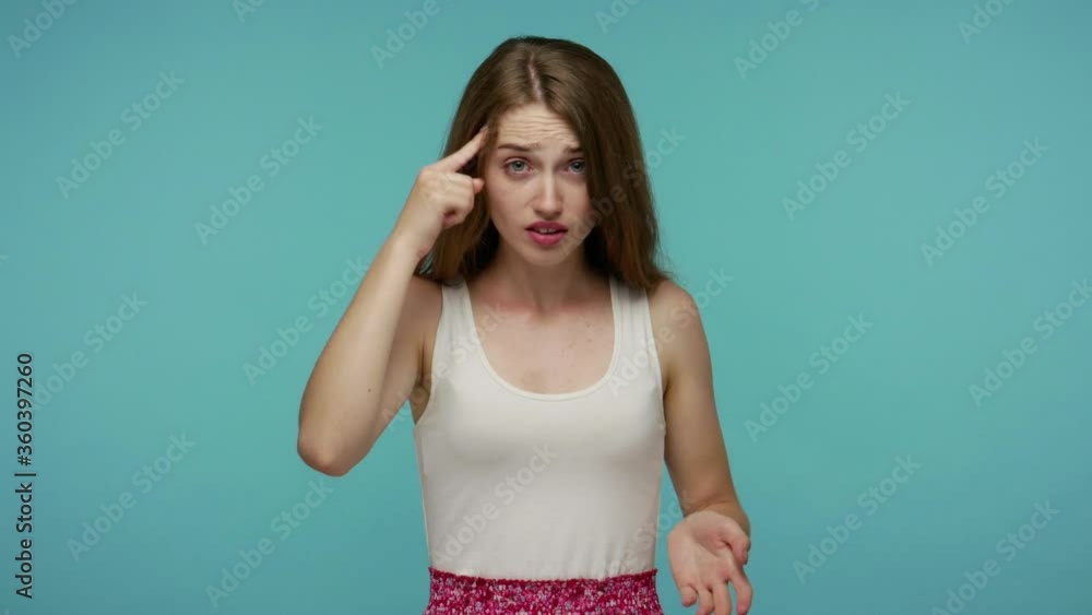 You are crazy, out of mind! Displeased annoyed girl in summer dress pointing at camera and showing stupid gesture, blaming some idiot for insane plan. indoor studio shot isolated on blue background You are crazy, out of mind! Displeased annoyed girl in summer dress pointing at camera and showing stupid gesture, blaming some idiot for insane plan. indoor studio shot isolated on blue background