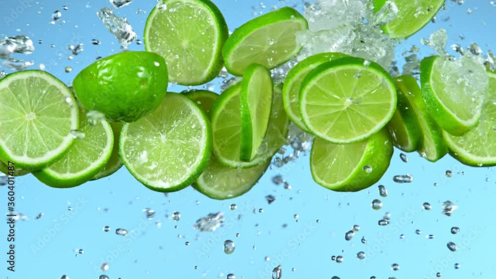 Super Slow Motion Shot of Flying Fresh Lime Slices and Water Side Splash on Light Blue Background at 1000fps. Super Slow Motion Shot of Flying Fresh Lime Slices and Water Side Splash on Light Blue Background at 1000fps.