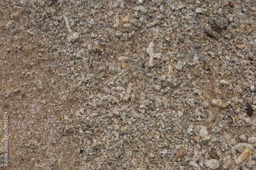 natural filled frame close up background wallpaper of a wet brown beige gravel beach rocks and stones surface