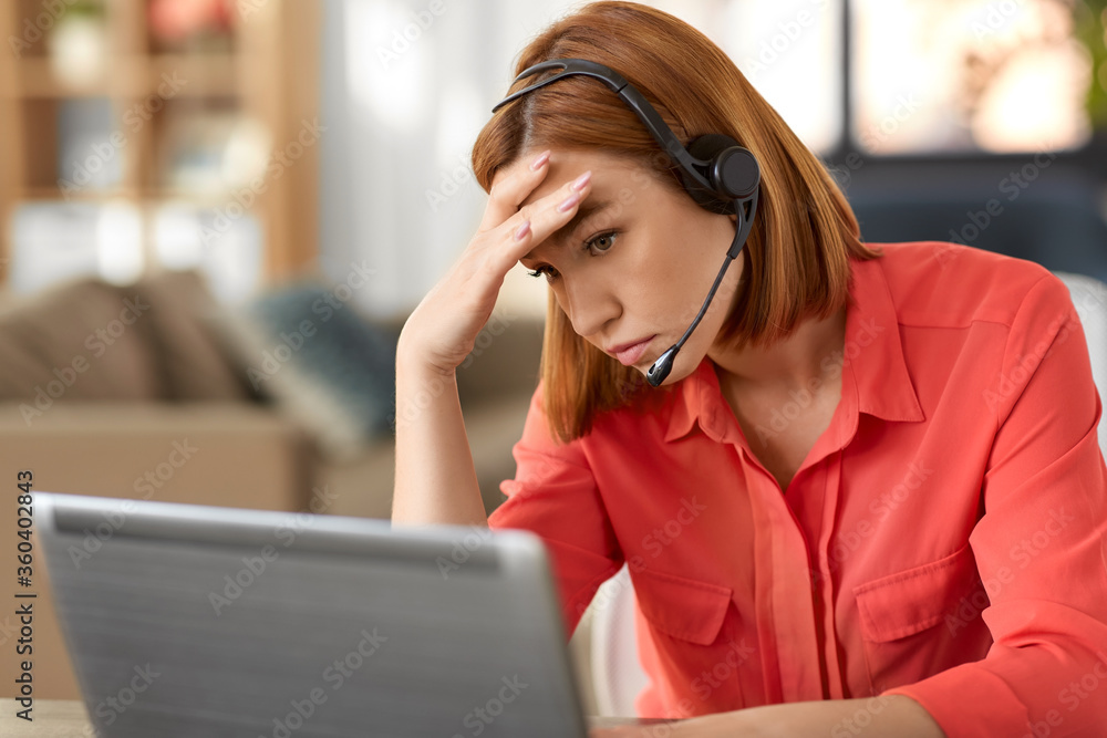 © Syda Productions - remote job, technology and people concept - sad young woman with headset and laptop computer having video conference at home office