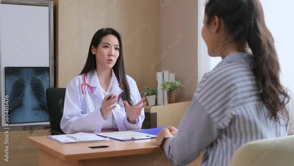 An Asian woman doctor is taking and notes about the details of the illness of her Asian woman patients. Obstetrician, healthy consultant concept. An Asian woman doctor is taking and notes about the details of the illness of her Asian woman patients. Obstetrician, healthy consultant concept.