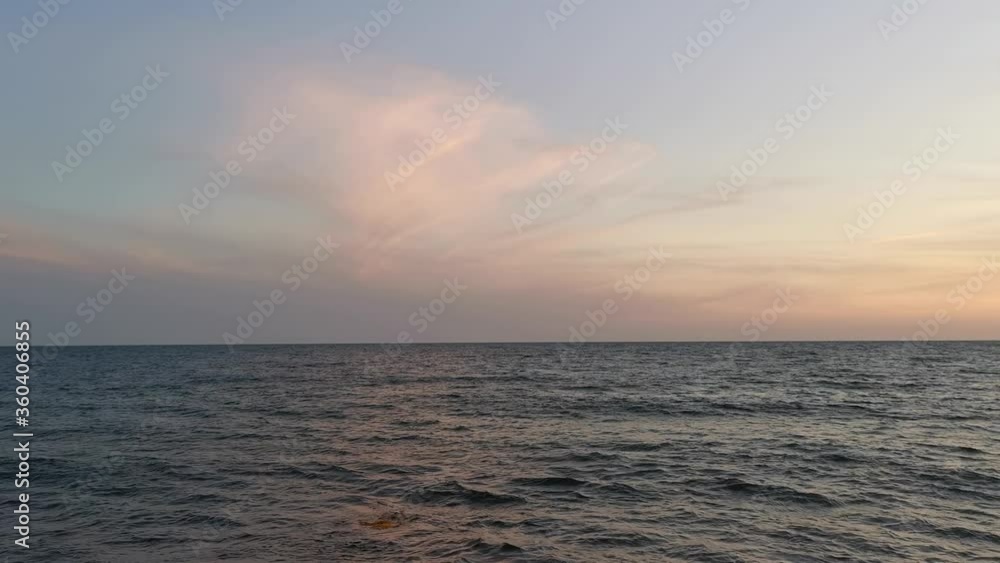 Calm sea and pink clouds. Relaxing sea background. Evening soft light. A sense of peace and tranquility. Small waves. Without people, the sea is far away. Calm sea and pink clouds. Relaxing sea background. Evening soft light. A sense of peace and tranquility. Small waves. Without people, the sea is far away.