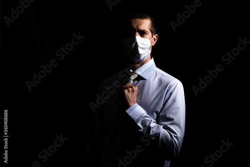 business successful man in a medical mask, slave and tie, portrait. on black