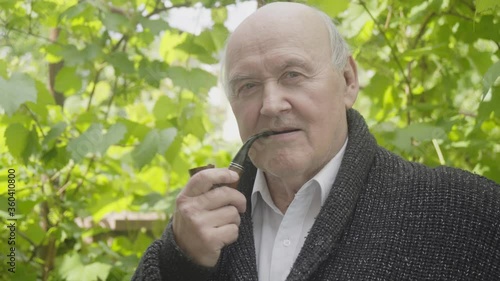 Senior man smoking tobacoo pipe and luking at camera photo