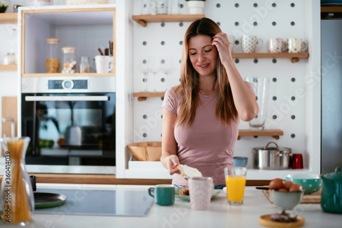 Young woman in kitchen. Beautiful woman preparing breakfast and drinking coffee. 