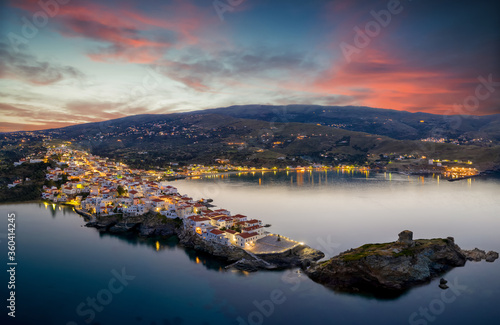 Luftaufnahme der Bucht von Andros mit beleuchteter Stadt und Hafen bei Dämmerung nach Sonnenuntergang Kykladen, Griechenland