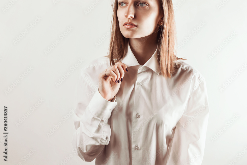 Portrait of young adult woman holding collar of white shirt with her hand, selective focus Portrait of young adult woman holding collar of white shirt with her hand, selective focus