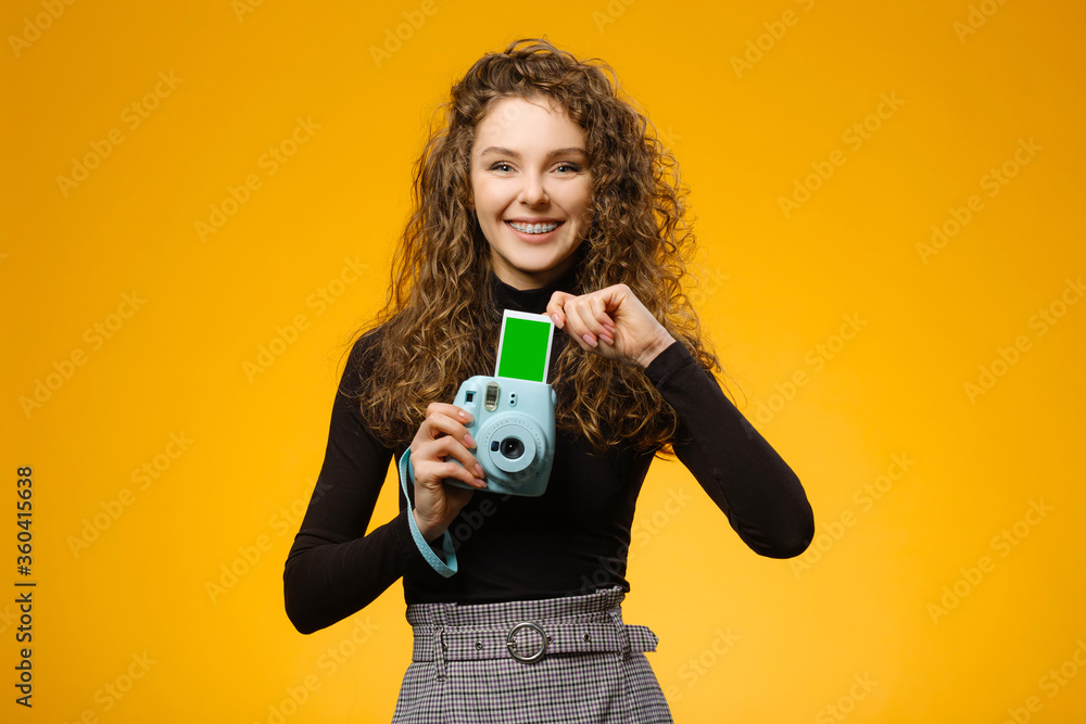 Beautiful girl with photo camera isolated on yellow background Beautiful girl with photo camera isolated on yellow background