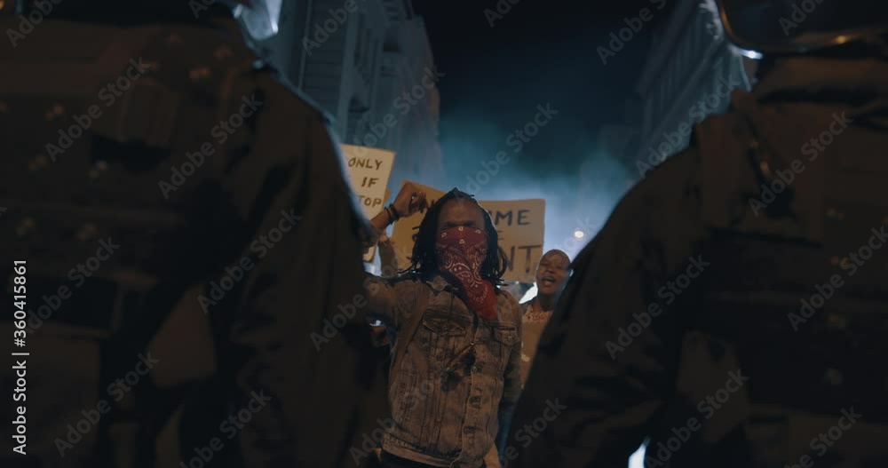 Group of furious protestors giving slogans in front of police force. Group of men and women demonstrating against police violence at night.
Group of furious protestors giving slogans in front of police force. Group of men and women demonstrating against police violence at night.