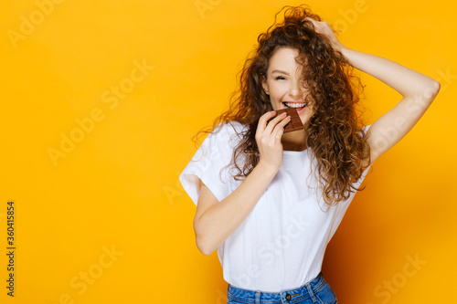 Happy girl with chocolate bar on yellow background