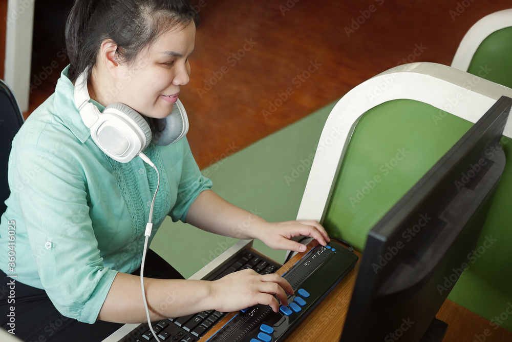 Asian young blind person woman with headphone using computer with