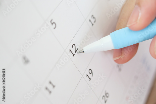 Hand with pen writing on calendar date
