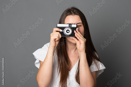 Smiling woman takes pictures with an old camera. Beautiful girl holds a camera.