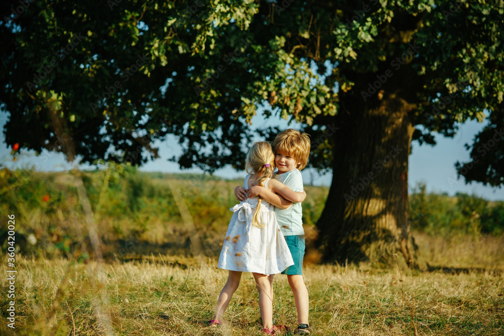 Happy little friends hugging on countryside. Child embrace each others. Funny kids, cute little boy hugging cute of yellow field. Valentines Day. Happy little friends hugging on countryside. Child embrace each others. Funny kids, cute little boy hugging cute of yellow field. Valentines Day.