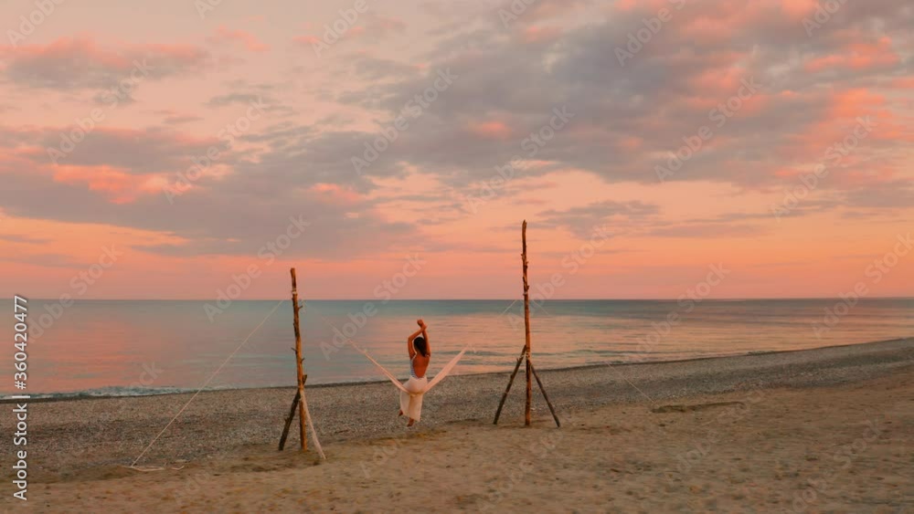 Giovane ragazza si dondola nell'altalena in riva al mare con un tramonto rosso infuocato. Giovane ragazza si dondola nell'altalena in riva al mare con un tramonto rosso infuocato.
