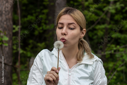 girl is blows away dandelion blowball