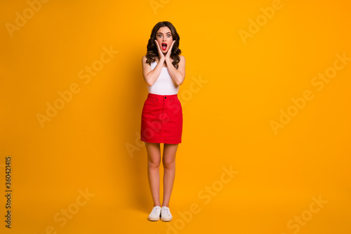 Full body photo of funny crazy lady cheerful person good mood open mouth amazing news arms cheekbones wear white casual singlet red mini skirt shoes isolated yellow color background