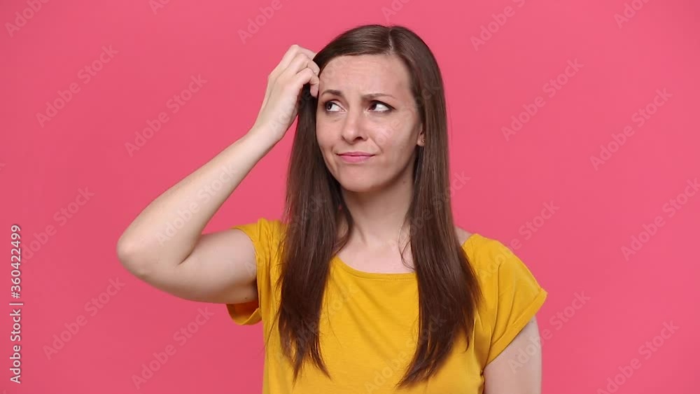 Smiling cute beautiful young woman in yellow t-shirt posing isolated on pink background studio. People lifestyle concept. Looks around thinks scratches at temple comes up with ideas raised finger up Smiling cute beautiful young woman in yellow t-shirt posing isolated on pink background studio. People lifestyle concept. Looks around thinks scratches at temple comes up with ideas raised finger up