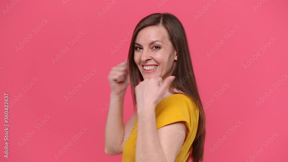 Back rear view of smiling brunette long hair young woman in yellow t-shirt posing isolated on pink background studio. People emotions lifestyle concept. Looking at camera turn round showing thumbs up Back rear view of smiling brunette long hair young woman in yellow t-shirt posing isolated on pink background studio. People emotions lifestyle concept. Looking at camera turn round showing thumbs up