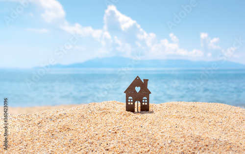 Canvas Print Lonely miniature house on deserted beach, blue sea and sky on background