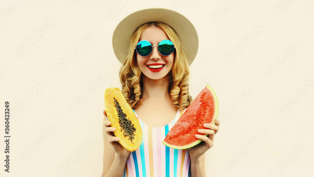 Obraz premium Summer portrait of happy smiling woman with fruits slice of watermelon and papaya wearing straw hat, sunglasses on white background