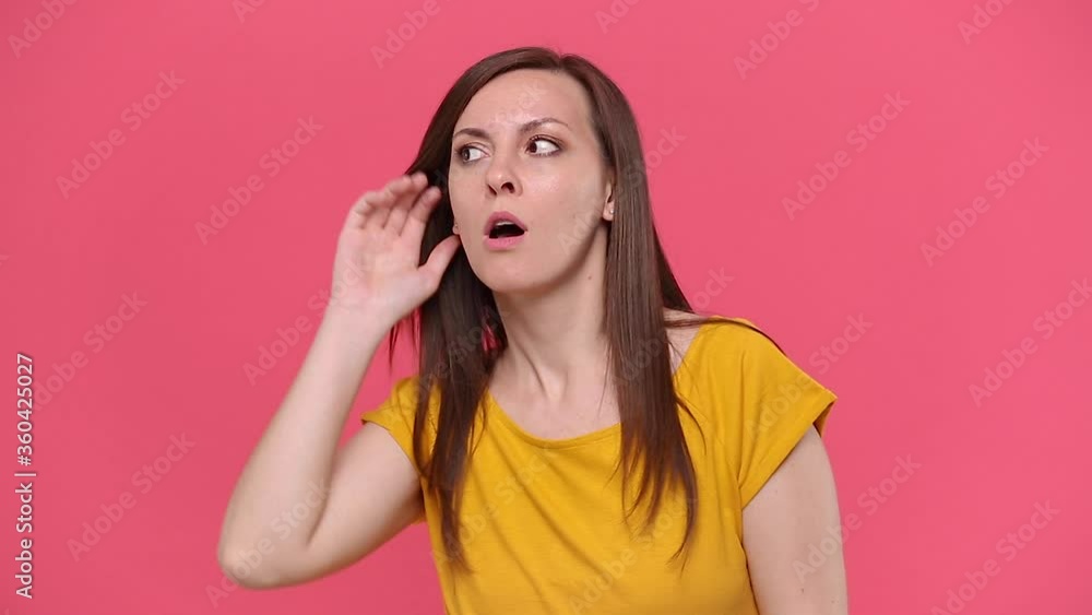 Fun woman in yellow t-shirt isolated on pink background studio People lifestyle concept Look aside try to hear you with hand at ear overhears secrets say hush be quiet with finger on lips shhh gesture Fun woman in yellow t-shirt isolated on pink background studio People lifestyle concept Look aside try to hear you with hand at ear overhears secrets say hush be quiet with finger on lips shhh gesture
