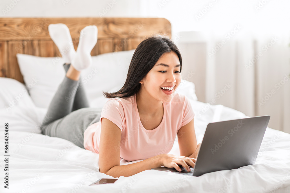 Asian Freelancer Girl With Laptop Working Online Lying In Bed Asian Freelancer Girl With Laptop Working Online Lying In Bed