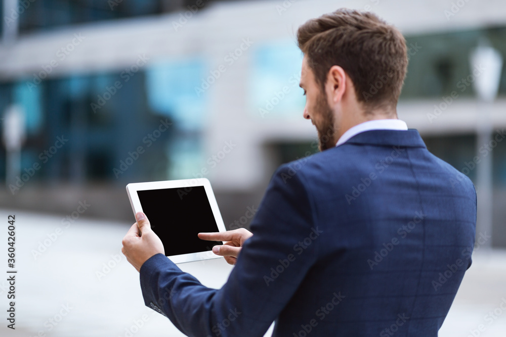Business executive holding tablet computer with blank screen near office building, mockup for design Business executive holding tablet computer with blank screen near office building, mockup for design