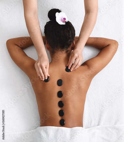 Hot stone massage for young black lady, top view