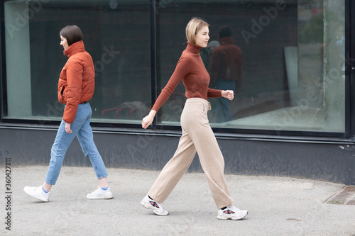 Two girls walking on the city street. Young woman outdoors.