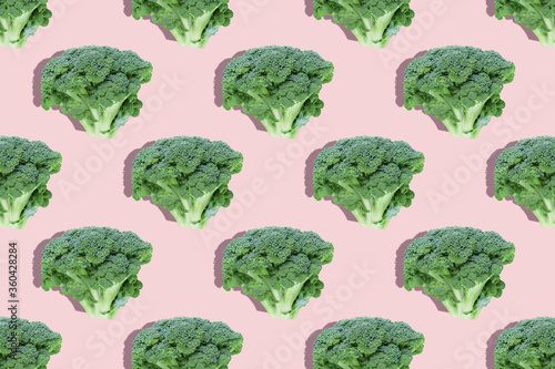 Seamless regular creative pattern of broccoli slices on a pink background.Top view.Photo collage,hard light,shadow,pop art design. Food blog, vegetable background. Printing on fabric, wrapping paper.