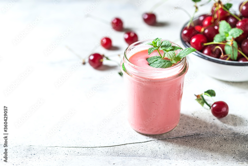 Yogurt with cherry, mint and and fresg berries on a light concrete background. Summer healthy dessert with berries. Yogurt with cherry, mint and and fresg berries on a light concrete background. Summer healthy dessert with berries.