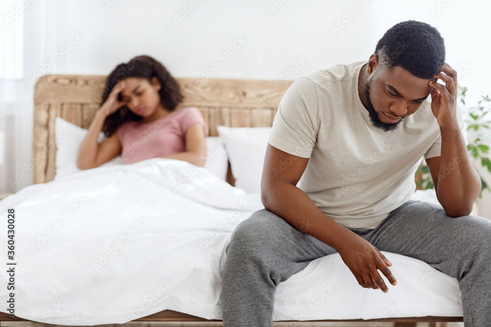Sad man and woman after quarrel sitting on bed Sad man and woman after quarrel sitting on bed
