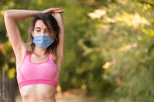 A girl stretching triceps after sports with the mask to avoid the Covid virus 19