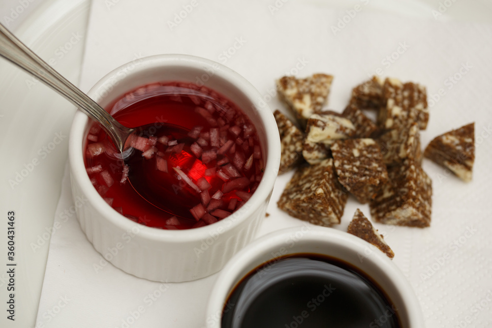 close up top view shot of two white cups with soy sauce and red vinegar mignonette marinade with shallots inside, on a white plate background close up top view shot of two white cups with soy sauce and red vinegar mignonette marinade with shallots inside, on a white plate background