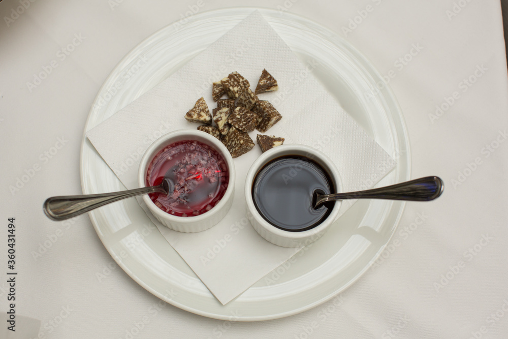 close up top view shot of two white cups with soy sauce and red vinegar mignonette marinade with shallots inside, on a white plate background close up top view shot of two white cups with soy sauce and red vinegar mignonette marinade with shallots inside, on a white plate background