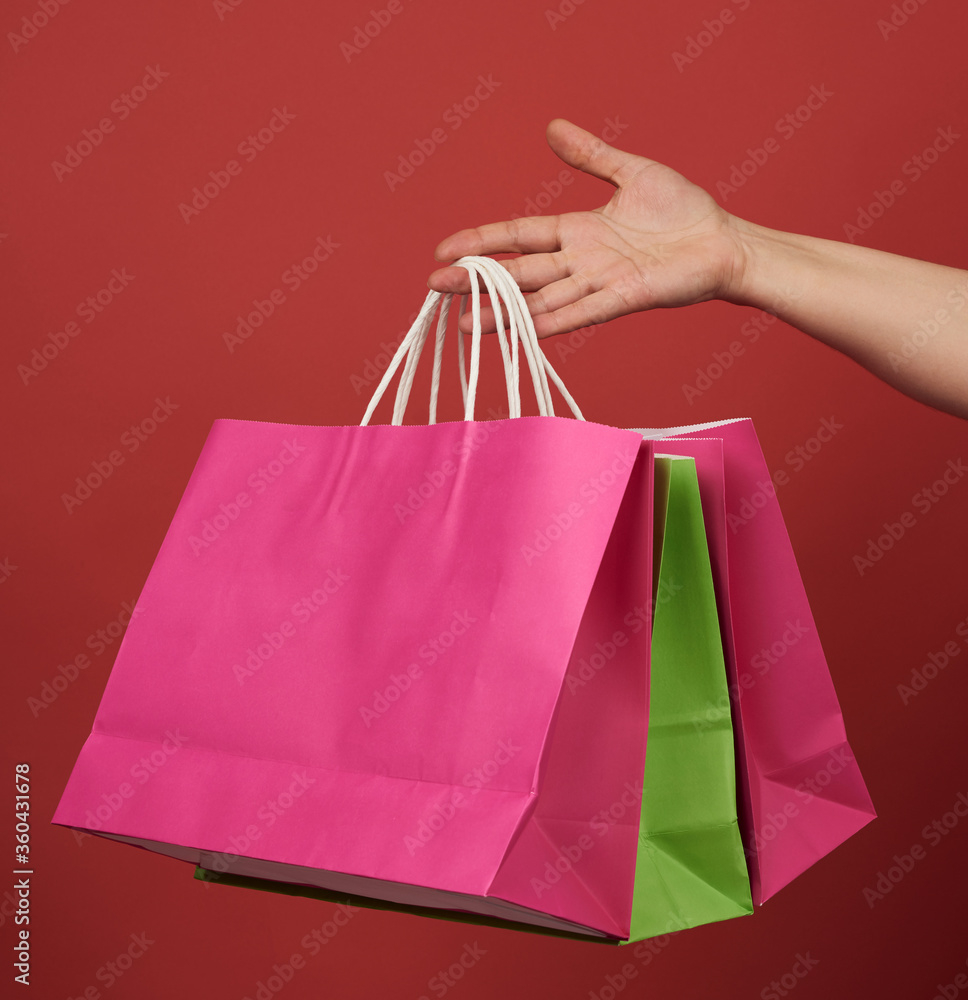 woman holds stack of paper bags on red background