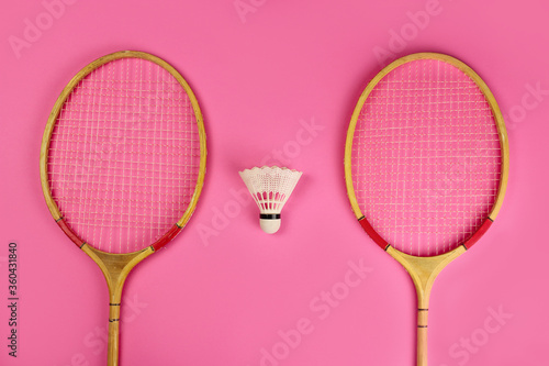Shuttlecock and badminton rackets on a pink background © Michael