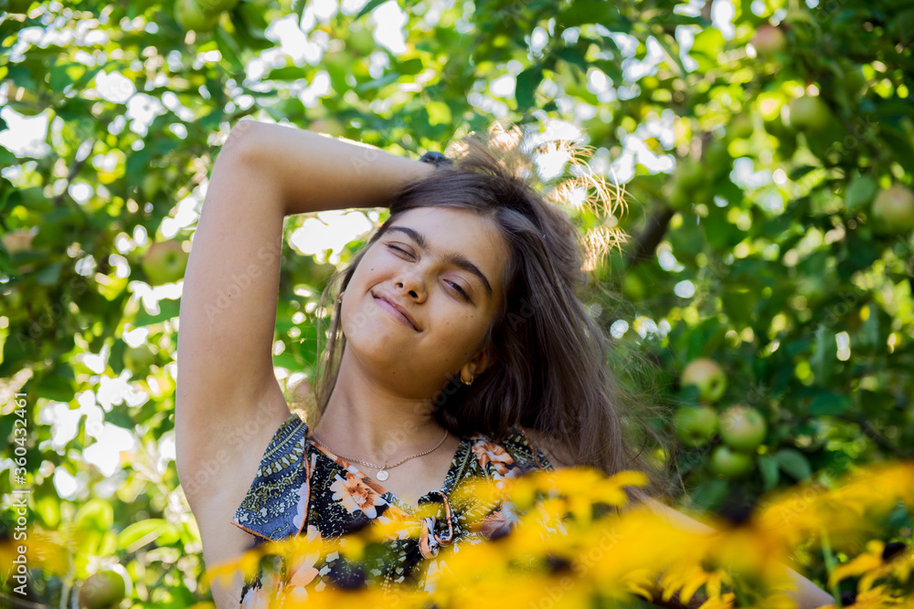 Portrait of a beautiful smiling girl outdoor. Morning in the village, summer morning. Girl with long hair in the apple orchard Portrait of a beautiful smiling girl outdoor. Morning in the village, summer morning. Girl with long hair in the apple orchard